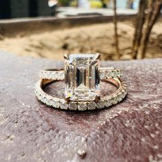 an emerald colored diamond ring on top of a rock