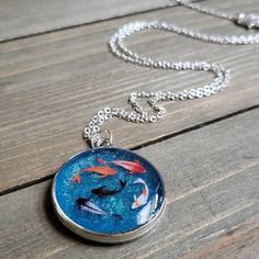 a necklace with fish on it sitting on top of a wooden table next to a chain