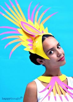 a woman wearing a yellow and pink hat with feathers on it's head, against a blue background