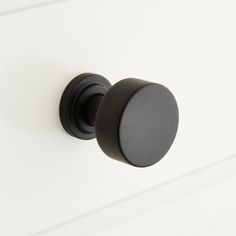 a black knob on a white cabinet door