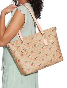 a woman in a green dress holding a beige purse with pink flowers on the side