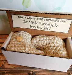 two crocheted slippers in a box with a card saying i have a surprise and it's certainly sweet