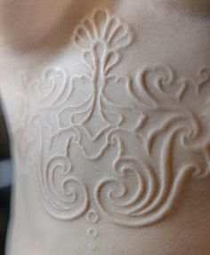 the back of a woman's stomach with an intricate design on her chest and side