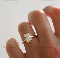 a woman's hand with a diamond ring on top of her finger, showing the center stone