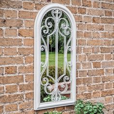 an arched window on the side of a brick wall next to a potted plant