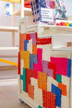 a multicolored crocheted blanket on top of a white cart in a store