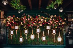 flowers and greenery are arranged on the wall behind tennis rackets with mirrors attached to them