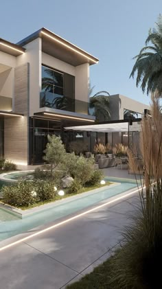 a modern house with an outdoor swimming pool and palm trees in the front yard at dusk