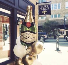 a bottle of champagne on top of balloons in front of a store