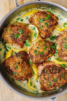 chicken with lemon sauce and parsley in a skillet on a wooden table top