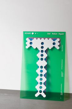 a green book with white and blue designs on it's cover, sitting on a table