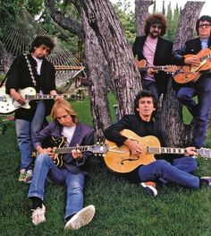 an image of a group of people playing guitars in the grass with trees and hammocks behind them