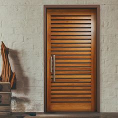 a modern wooden door in front of a white brick wall with a sculpture on the side