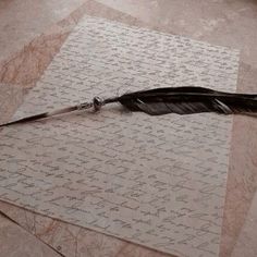 a feather quill laying on top of a piece of paper