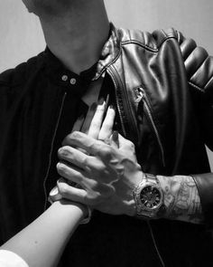 two people are holding each other's hands in black and white, one is wearing a leather jacket