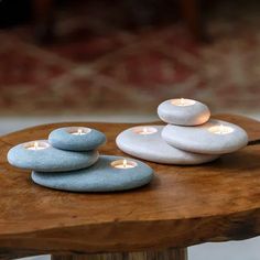 three lit candles are placed on top of some rocks in the shape of pebbles, sitting on a wooden table