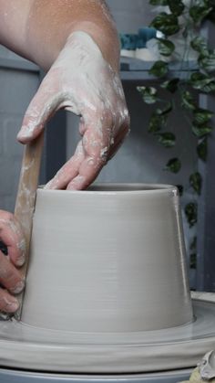 a person is making a pot on a potter's wheel with one hand and the other