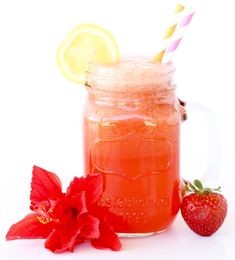 a strawberry lemonade drink in a mason jar with strawberries and a flower on the side