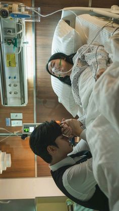 a man and woman in hospital gowns looking at each other's earphones