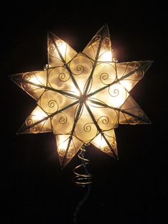 a lighted star with swirls on it in the dark