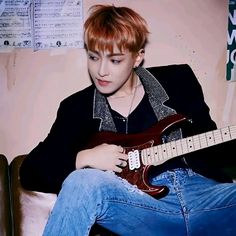 a person sitting on a chair with a guitar in their lap and looking at the camera