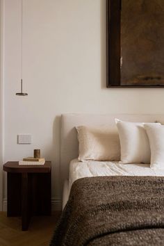 a bedroom with a bed, nightstand and painting on the wall