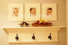 a shelf with three pictures on it and two birds sitting on the ledge above them