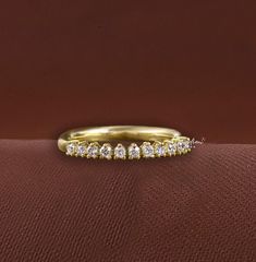 a yellow gold wedding band with five round diamonds on the top and bottom, sitting on a red cloth