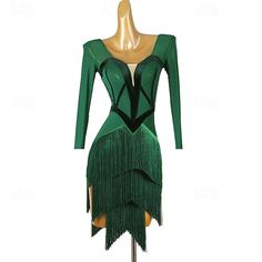 a green dress with long sleeves and fringes on the skirt is sitting on a mannequin