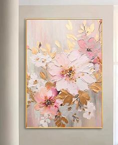 a painting hanging on the wall above a couch in front of a window with white and pink flowers