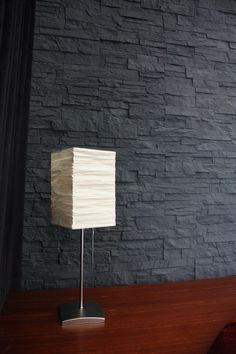 a lamp sitting on top of a wooden desk next to a brick wall in a room