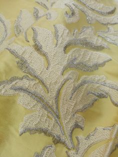 the fabric is yellow and grey with silver flowers on it's side, as well as an intricate design