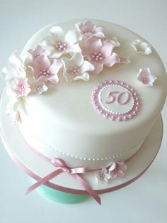 a white cake with pink flowers and the number 50 on it's bottom tier