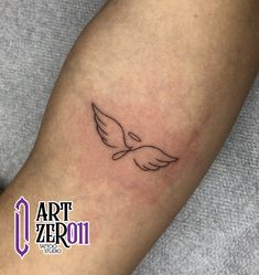 a small tattoo on the leg of a woman's arm with an angel wing