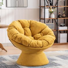 a yellow chair sitting on top of a rug in front of a book shelf filled with books