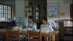 two people sitting at a table with books