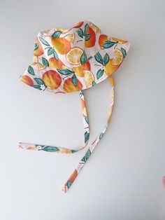 "Handmade brimmed orange print with soft pink background sun hat Breathable 100% cotton fabric Cotton lining | satin lining Measurements: Tie length for all - 16\" / 30-31 cm 0-3 months - 13\" / 33cm 3-6 months - 15\" / 38 cm 6-12 months - 17\" / 43cm 12-24 months - 18.5\" / 46-48 cm 2-4 years - 20\" / 50 cm 4-7 years - 20.5\" / 52 cm 7-12 years - 21.5\" / 54 cm Adult Small - 22\"/56 cm Adult Medium - 23\"/58 cm Adult Large - 24\"/60 cm Care instructions: Machine wash in cold water, gentle dry, Adjustable Orange Sun Hat For Vacation, Orange Summer Sun Hat For Vacation, Adjustable Orange Sun Hat For Summer, Orange Brimmed Sun Hat For Vacation, Orange Brimmed Sun Hat For Summer, Orange Sun Hat For Summer, Adjustable Summer Sun Hat In Orange, Summer Orange Adjustable Sun Hat, Adjustable Orange Summer Sun Hat