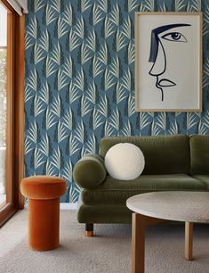 a living room with a green couch and blue wallpaper