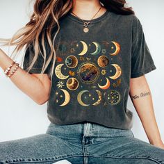 Watercolor Moon Phase Tee in Comfort Colors with 15 Unique and Playful Phases: Introducing our beautiful and whimsical Moon Phase T-shirt, perfect for anyone who loves celestial designs and wants to add a touch of magic to their wardrobe. Featuring 15 different fun and playful moon phases scattered across a stunning watercolor print, this t-shirt is truly one-of-a-kind. The eye-catching watercolor print features 15 unique and playful moon phases, each one more whimsical and fun than the last. The soft, muted colors of the print blend beautifully with the vintage-inspired Comfort Colors material, giving the shirt a classic, rustic feel. Whether you're a lover of all things celestial or just looking for a fun and playful shirt to add to your collection, our Moon Phase T-shirt is the perfect Bohemian Short Sleeve T-shirt With Sun And Moon Design, Celestial Moon Print Crew Neck T-shirt, Celestial Short Sleeve Tops With Moon Print, Festival Graphic Tee With Moon Print, Graphic Tee With Moon Print For Festival, Festival T-shirt With Moon Print And Short Sleeves, Casual Moon Print Tops For Festival, Bohemian Summer Tops With Moon Print, Bohemian Cotton Tops With Sun And Moon Design