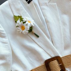 a white suit with flowers on the lapel and belt is seen from above,