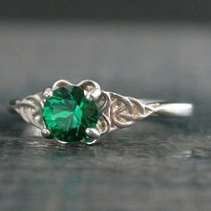 Green Celtic Ring Emerald Ring May Birthstone St. Patrick's Day Ring Trillion Ring Irish Engagement Ring Green Stone Ring Celtic Knot RingFeaturing an interwoven Celtic knot design to each side of the stone, the band tapers for a very elegant look and then flairs out again for a sturdy, yet feminine band. The 6mm Emerald of your choice is expertly set in a secure 4 prong setting that nestles the stone in a subtle four leaf clover design.The top of the ring spans 7mm wide at it's widest point and May Birthstone Jewelry With Stone Setting, Sterling Silver Crystal Ring With Accent Stones For May, Sterling Silver Rings With Jewels For Gifts, Green Promise Ring Jewelry With Round Stone, Promise Ring Jewelry With May Birthstone Center Stone, Adjustable Emerald Rings With Birthstone, Adjustable Sterling Silver Ring With May Birthstone, Crystal Ring With Center Stone For May Birthstone Gift, Sterling Silver Jewelry For May Birthstone In Round Band