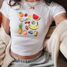 We love this fun, colorful Fruit design Baby Tee! This adult sized tee is soft and super comfy and is made of 52% cotton and 48% polyester for a luxurious lightweight stretch. The designs are printed with DTF which delivers a vivid, detailed design with a textured feel. This tee is a perfect blend of coquette fashion and nostalgic Y2K vibes, making it a trendy addition to your casual wardrobe. Made with soft, comfortable material, it's ideal for everyday wear or for making a statement at your ne Y2k Style Short Sleeve T-shirt With Fruit Print, Pink Fruit Print Tops For Summer, Cute White Tops With Fruit Design, Summer Y2k T-shirt With Fruit Print, Playful Colorful Short Sleeve Top, Multicolor Cartoon Print Y2k Tops, Fitted Summer T-shirt With Strawberry Print, Fitted Strawberry Print T-shirt For Summer, Pink Fruit Print Tops For Spring