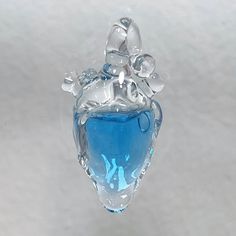 a blue heart shaped glass ornament hanging from a hook on a white surface