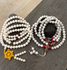 Beautiful Howlite Mala from Nepal and Mountain shell beads Mala necklace. You can choose between the mala that is made with howlite beads (white with gray) and mix metal beads from Nepal, or the all white mala necklace, which is made with mountain shell beads and a yellow mantra symbol. A unique praying mala that can be used as a necklace or as an ornament. The mala has no clasp, you wear it over the head. --The Mala with the metal beads and the red beads has a total length of 48.2cm- 19 inch lo White Adjustable Mala With Gemstone Beads, Adjustable White Mala With Gemstone Beads, Adjustable White Mala With 8mm Beads, Adjustable White Gemstone Beads Mala, White Spiritual Necklace With Polished Beads, White Gemstone Beaded Necklaces For Meditation, White Beaded Necklaces With Gemstone Beads For Healing, White Hand-strung Beaded Necklaces With Round Beads, Spiritual White Necklaces With Polished Beads