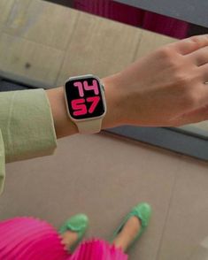 a person wearing a watch with pink numbers on their wrist and green shoes is standing in front of a mirror