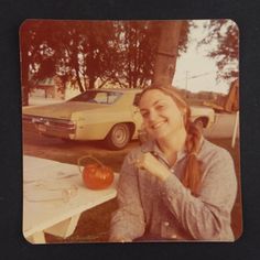 a woman sitting at a table with an apple in front of her