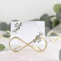 an elegant place card holder is adorned with gold leafy vines and leaves, along with two matching napkin holders