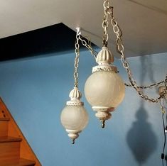 two chandeliers hanging from the ceiling in a room with blue walls and stairs