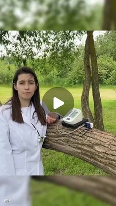 a woman standing next to a tree with an old cell phone on top of it