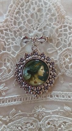 "With beautiful watery color and wonderful clarity, encased in an antiqued silver tone setting, our 'Aquarius, The Water Bearer' brooch measures 2.5 inches in length. The artwork is set under a high quality glass dome.  Every item in our shop is handmade, and created with loving care.   Please note: The glare on the cameo occurs from the photo and is not a blemish on the piece. Our cameos are resistant but not waterproof and should not be submerged in water or worn when swimming or bathing. For your timeless style! Your treasures come tucked into a lovely organza bag.  If your order is being sent directly to a gift recipient, we are delighted to take part in your thoughtfulness, and are happy to include a card with your personal message.  Simply include your message in the \"message to sel Silver Medallion Brooches As A Gift, Silver Art Nouveau Brooches As Gift, Silver Art Nouveau Brooches For Gifts, Silver Medallion Brooches For Collectors, Vintage Brooch With Antique Finish, Handmade Artistic Silver Brooch, Silver Cabochon Brooches Collectible, Antique Silver Vintage Brooches As Gift, Constellation Aquarius